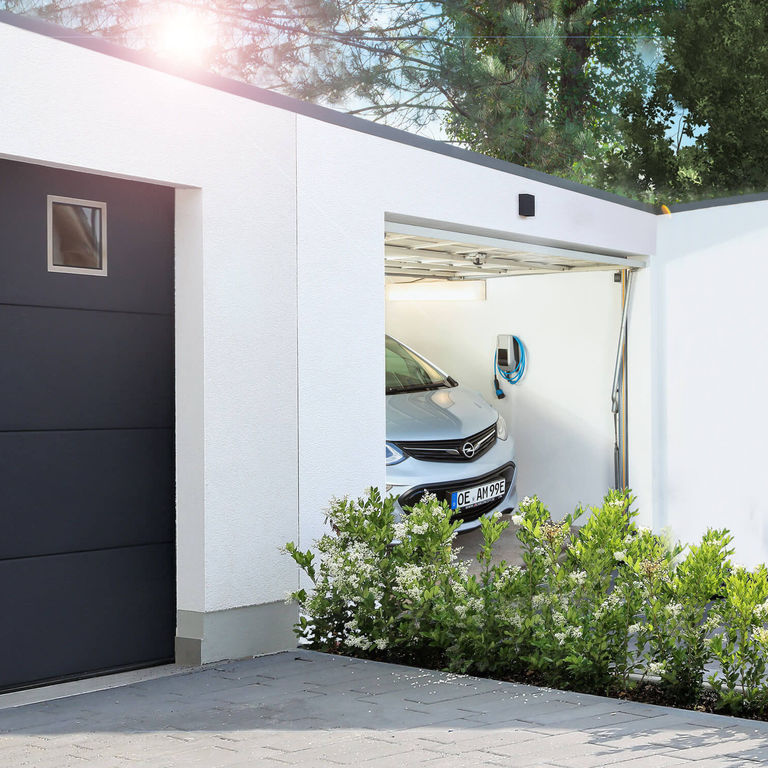 In einer schmalen Garage hängt die MENNEKES Wallbox AMTRON® Compact 2.0 an der Wand.